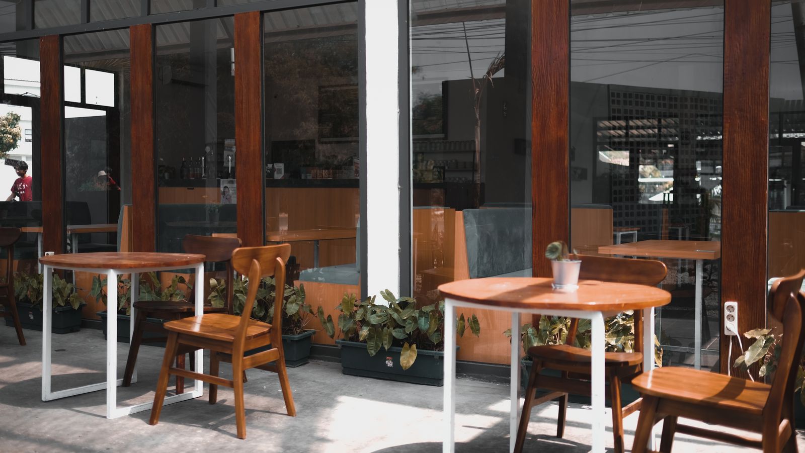 Terrasse et fenêtres d'un café moderne avec plantes.